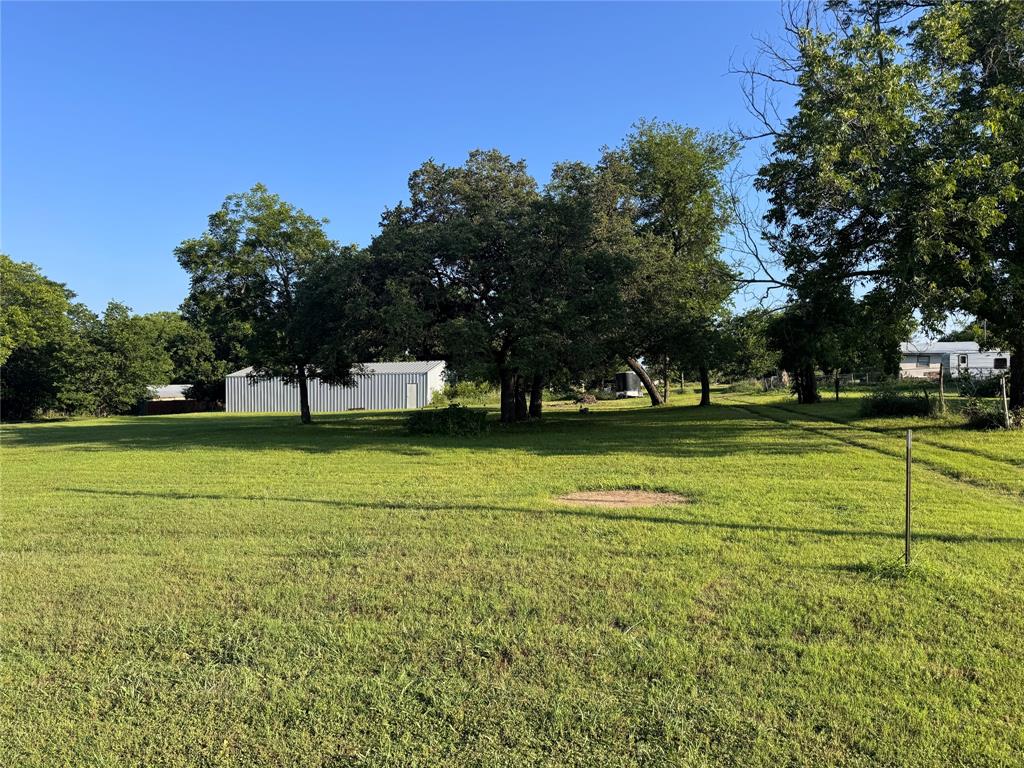 1002 6th Street Blanket, TX 76432 - Photo 1 of 16 Expansive green lawn with mature trees and visible outbuilding