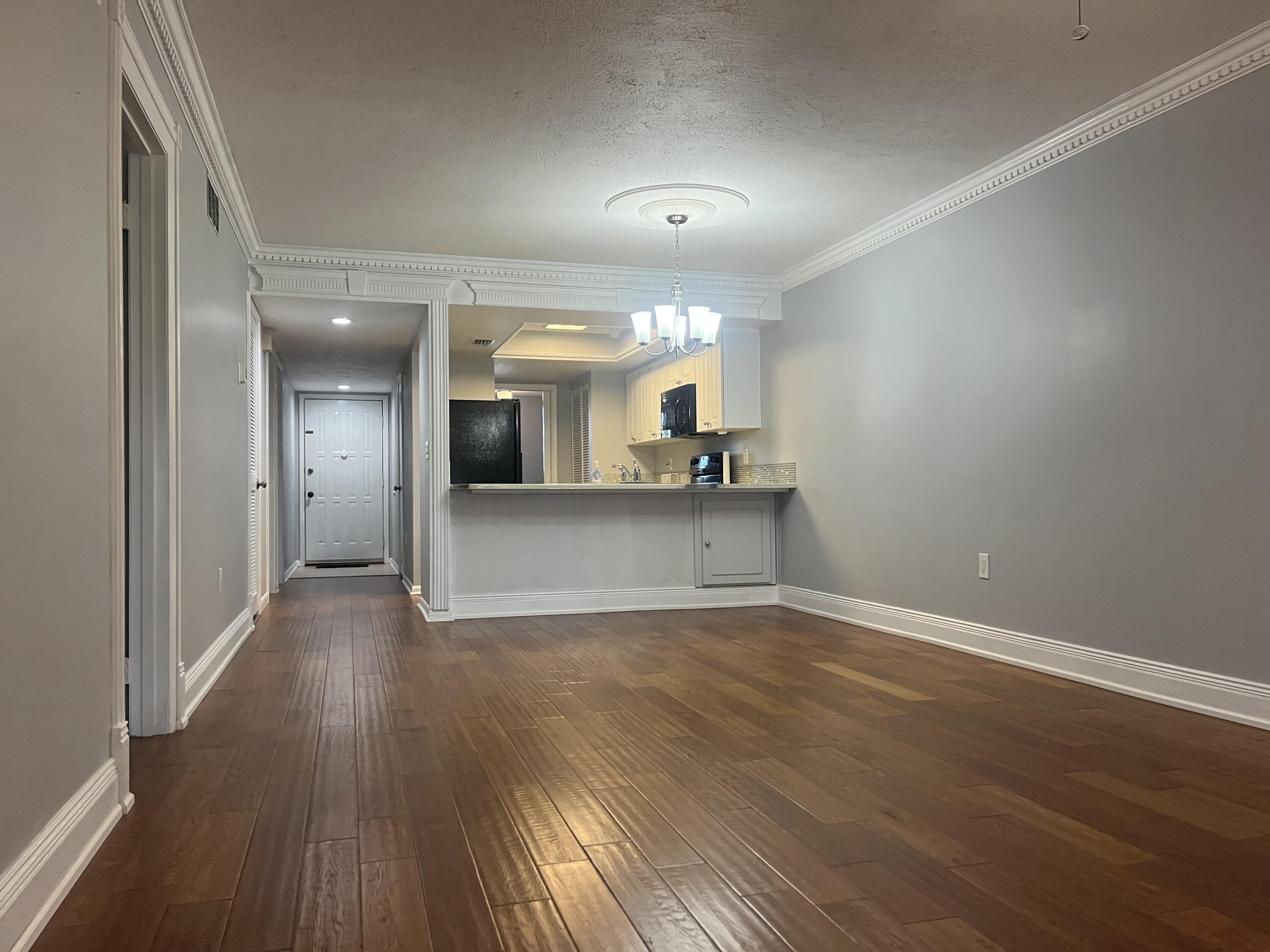 1675 South Fiske Boulevard, Unit 155 Rockledge, FL 32955 - Photo 3 of 24 an empty room with wooden floor and a kitchen