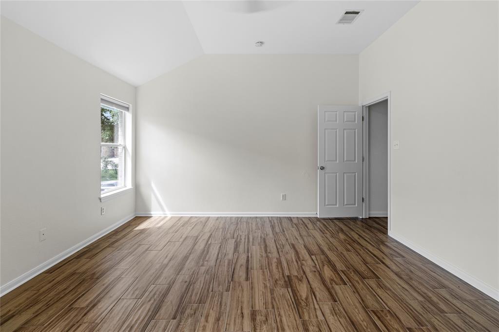 1011 St Helena Drive Leander, TX 78641 - Photo 9 of 11 Empty room with lofted ceiling and dark wood-style flooring