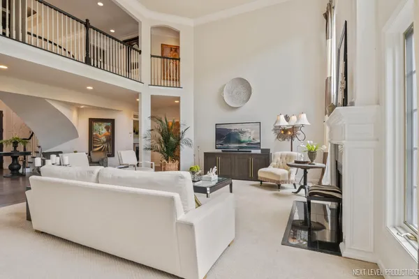 a living room with furniture a fireplace a large window and potted plants