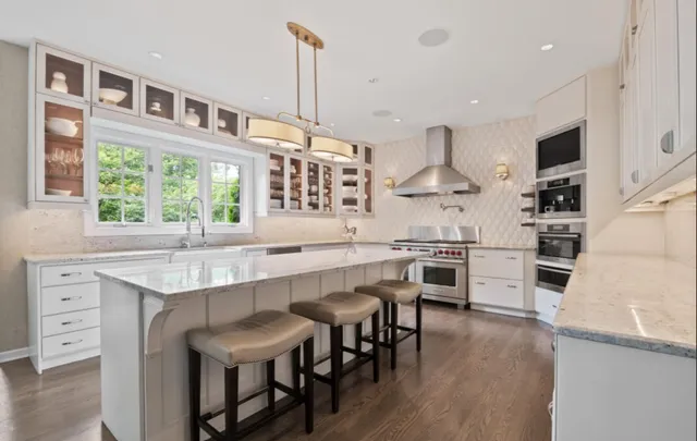 a kitchen with stainless steel appliances a stove a sink dishwasher a oven with white cabinets and wooden floor