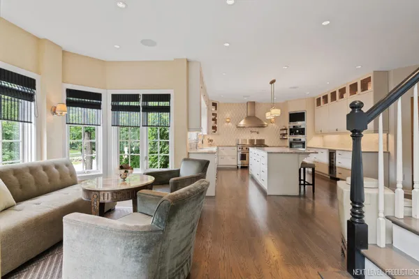 a kitchen with stainless steel appliances granite countertop a stove a sink dishwasher and a dining table with wooden floor