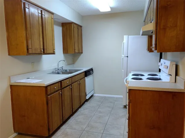 a utility room with stainless steel appliances granite countertop a sink stove and refrigerator