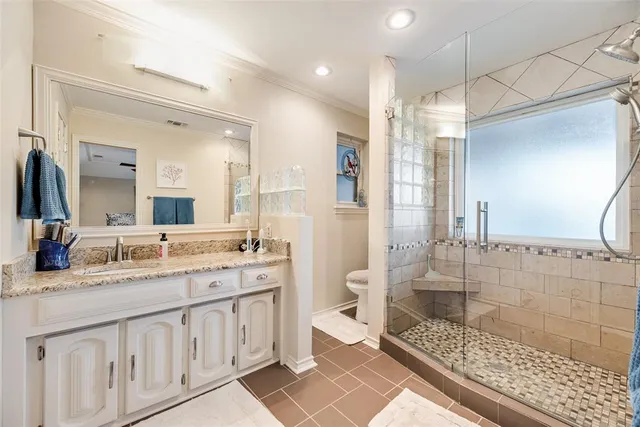 a bathroom with a granite countertop sink a toilet a mirror and shower