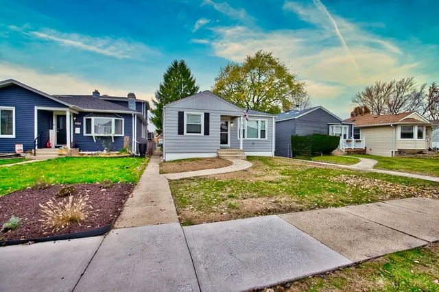 a front view of a house with a garden and trees