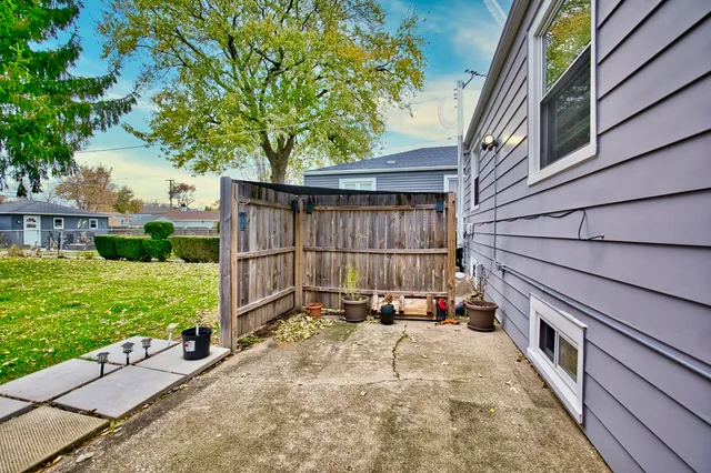 a view of backyard with large trees and a wooden fence