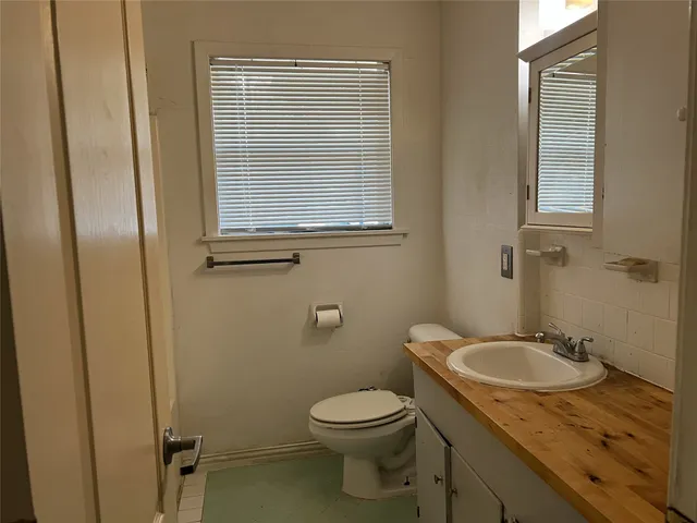 a bathroom with a granite countertop toilet sink and mirror