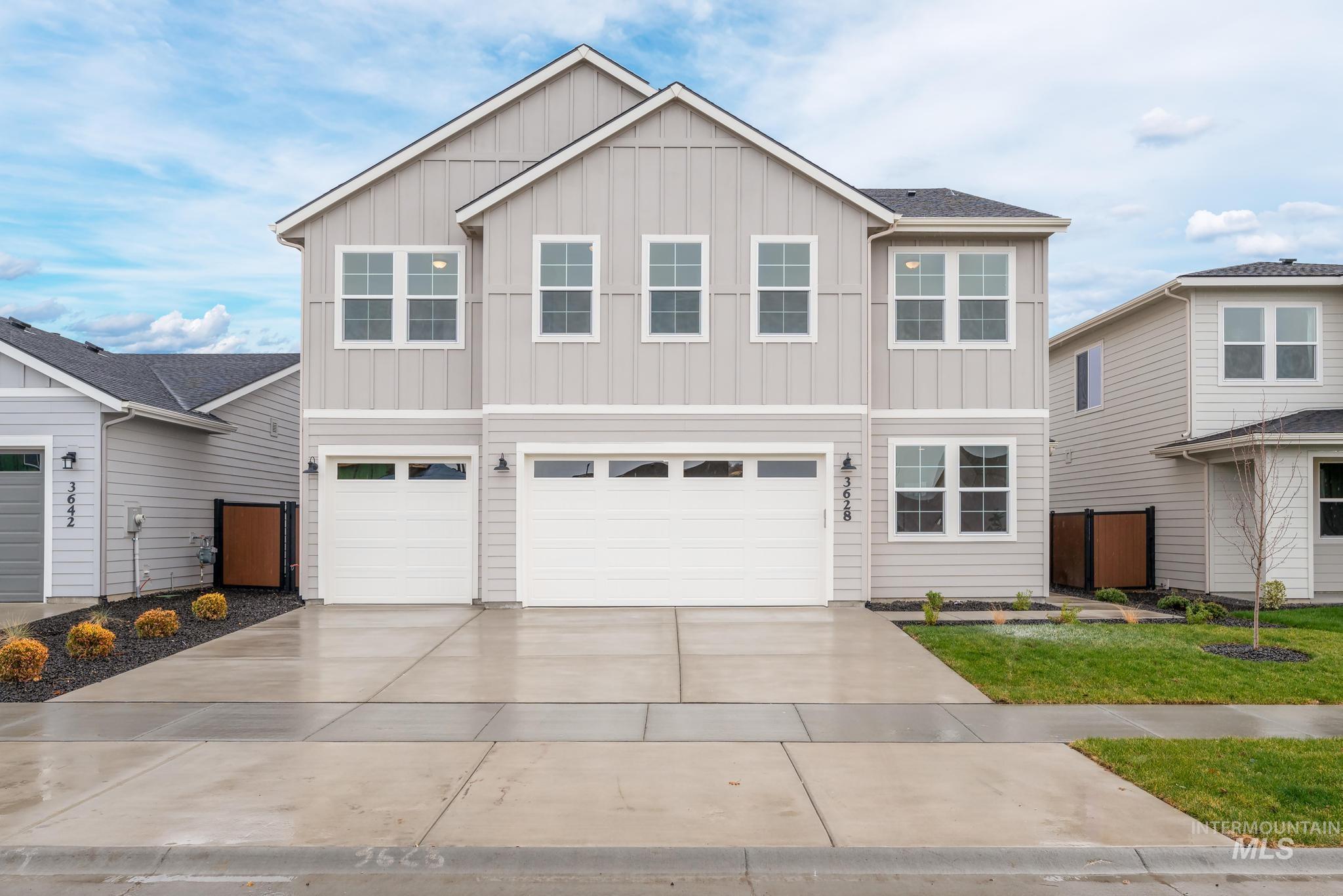 View of front of home with an attached garage, board and batten siding, driveway, and a front lawn