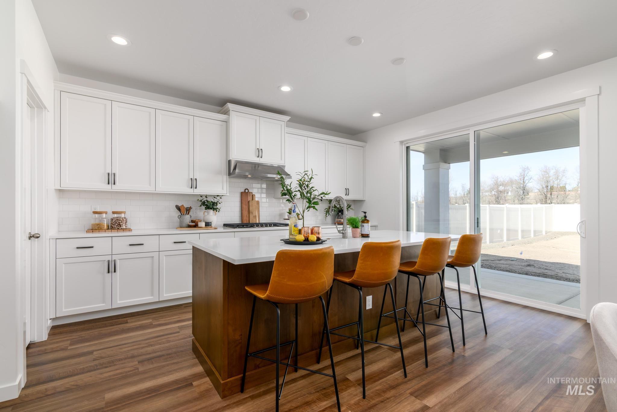 1244 Grassland Street Middleton, ID 83644 - Photo 5 of 10 Dual tone kitchen with two tone cabinets, an island with sink, dark wood finished floors, a breakfast bar, and recessed lighting
