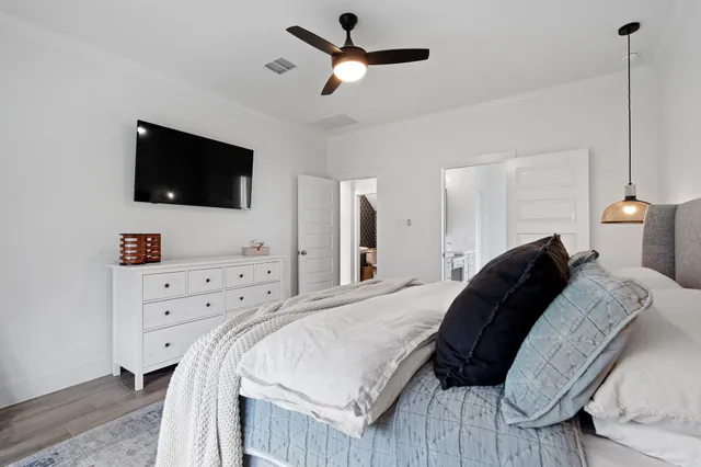 a bedroom with a bed a flat screen tv and a chandelier