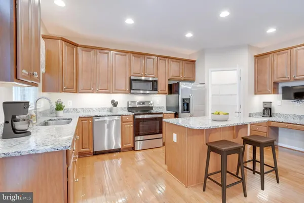 a kitchen with kitchen island granite countertop wooden cabinets and white appliances