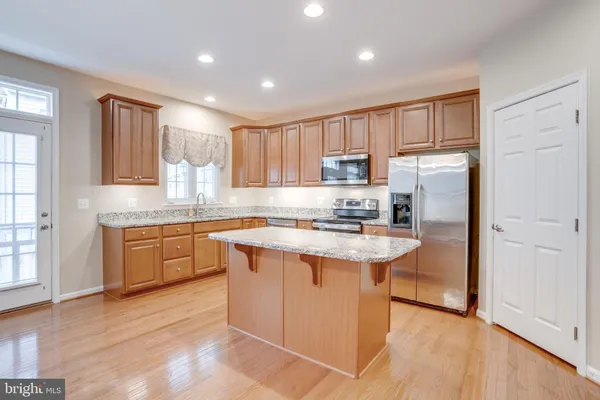 a kitchen with kitchen island granite countertop appliances cabinets and a sink