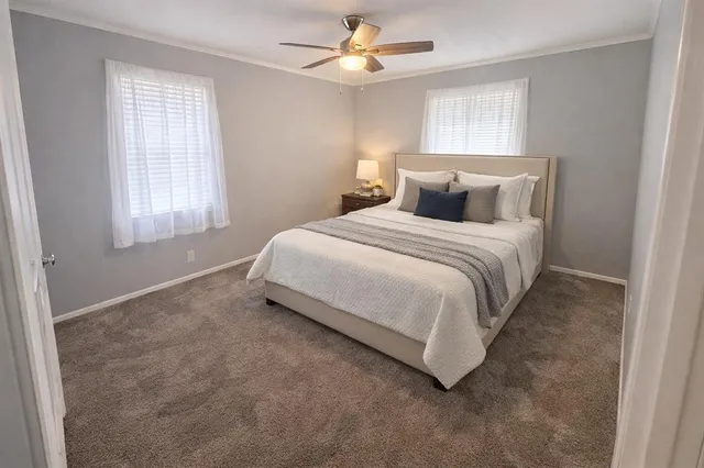 a bed sitting in a bedroom next to a window and a chandelier