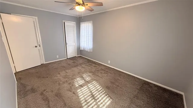 an empty room with a chandelier fan and windows