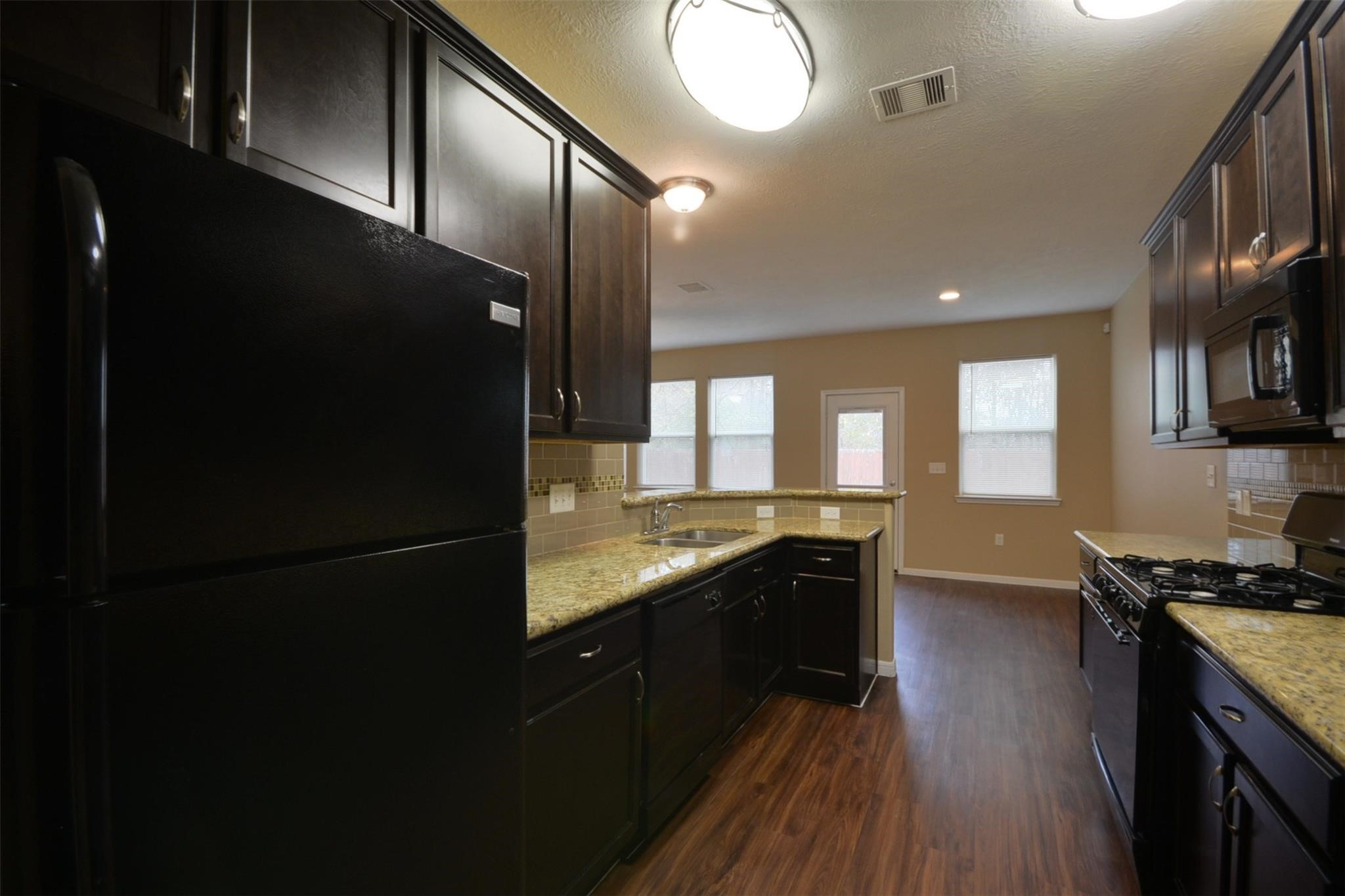 106 Eddy Street, Unit B Humble, TX 77338 - Photo 7 of 22 a kitchen with granite countertop stainless steel appliances a refrigerator a stove a sink and a microwave oven