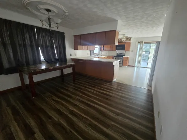 a kitchen with kitchen island wooden cabinets stainless steel appliances a sink and living room view