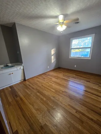 a view of an empty room with wooden floor and a window