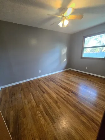 a view of an empty room with window and wooden floor