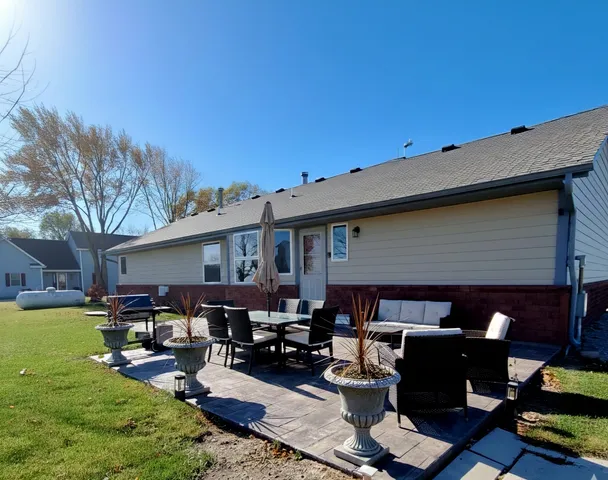 a backyard of a house with dining table and chairs with plants and wooden fence