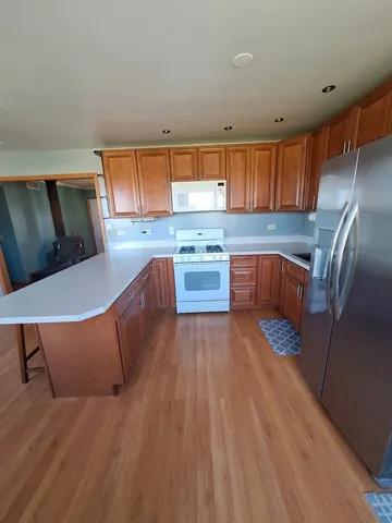 a kitchen with stainless steel appliances granite countertop a stove a sink dishwasher and a refrigerator with wooden floor
