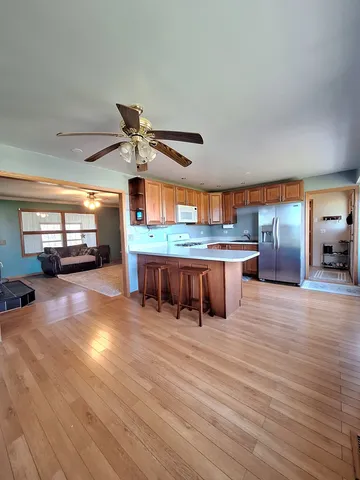 a view of a kitchen with stainless steel appliances granite countertop a stove and a wooden floors