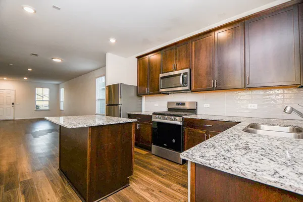 a kitchen with stainless steel appliances granite countertop wooden cabinets a stove top oven a sink and dishwasher