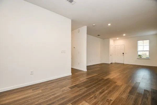 an empty room with wooden floor and window