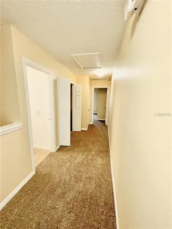 a view of a hallway with wooden floor and a bathroom