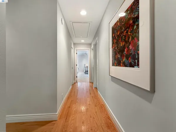 a view of a hallway with wooden floor and a bathroom