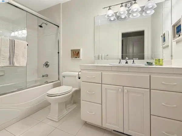 a bathroom with a toilet a sink a mirror a shower a vanity and window