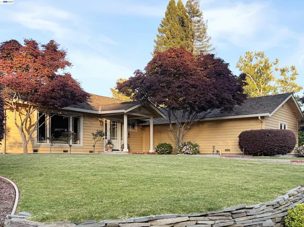 a front view of a house with a garden and trees