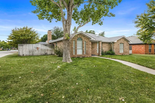 a view of a house with a yard and a large tree
