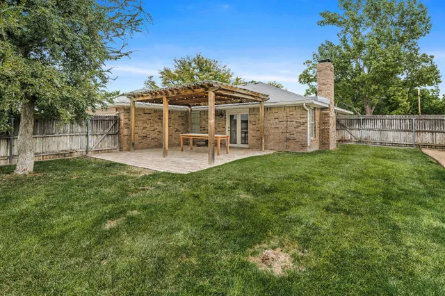 a view of a chair and table in backyard of the house