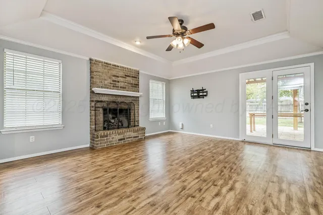 a view of an empty room with wooden floor fireplace and a window