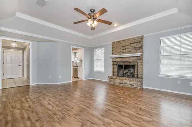 an empty room with fireplace chandelier fan and windows
