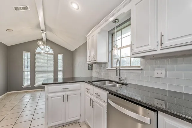 a kitchen with stainless steel appliances granite countertop a sink a stove and cabinets
