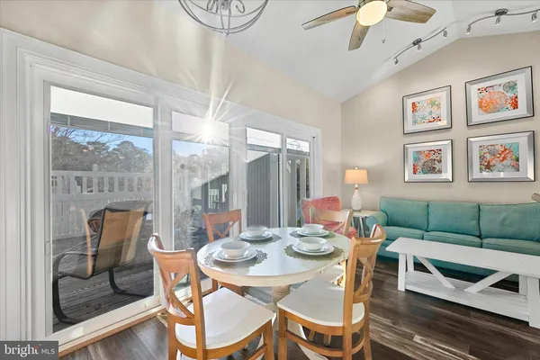 a open dining room with stainless steel appliances kitchen island granite countertop a dining table and chairs with wooden floor