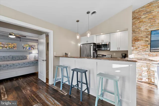 a kitchen with stainless steel appliances granite countertop a sink a stove and a wooden floors