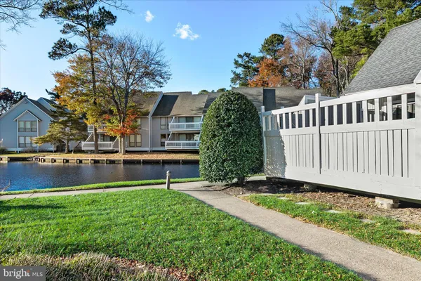 a kitchen with stainless steel appliances kitchen island granite countertop a refrigerator a stove a dining table and chairs with wooden floor