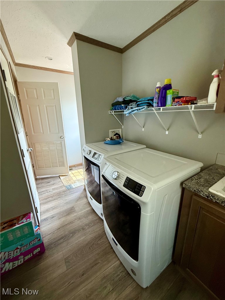 2306 Gordon Road Northwest Dover, OH 44622 - Photo 21 of 26 Washroom featuring independent washer and dryer, ornamental molding, wood finished floors, and cabinet space