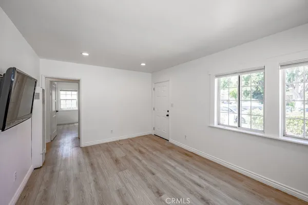 an empty room with wooden floor fan and windows