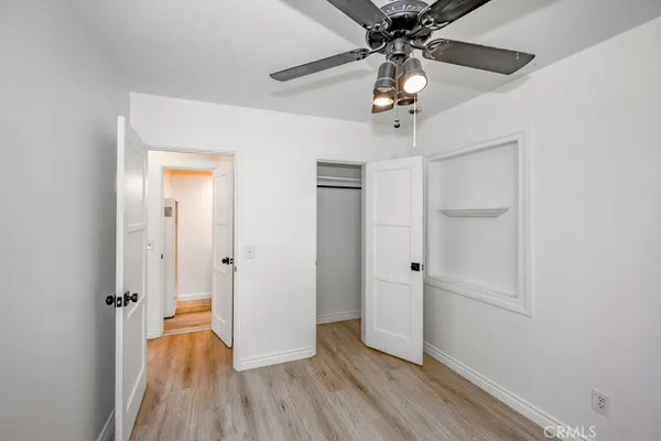 a view of a hallway with wooden floor and chandelier fan