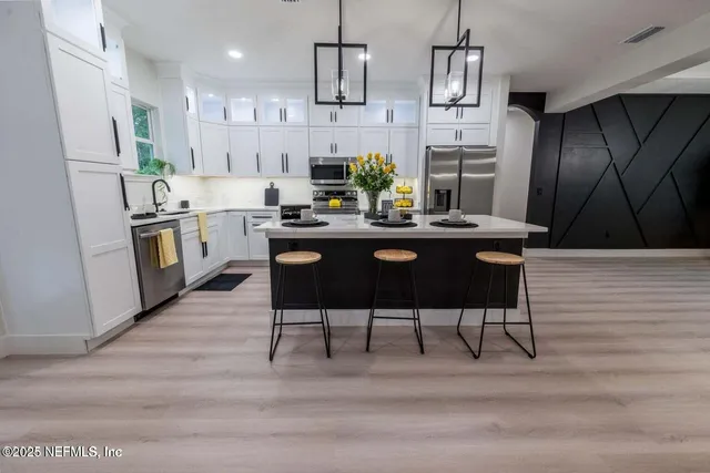 a kitchen with stainless steel appliances kitchen island granite countertop a table chairs stove and refrigerator