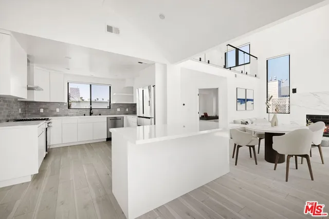 a large white kitchen with cabinets a sink a window and stainless steel appliances