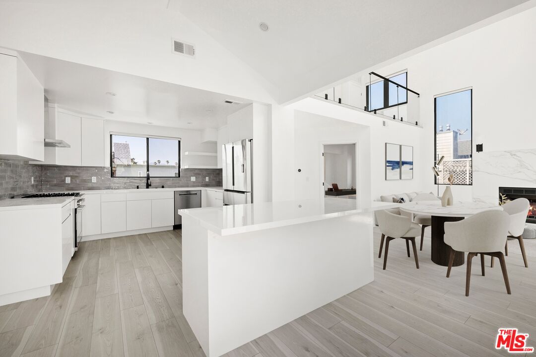 2225 4th Street, Unit B Santa Monica, CA 90405 - Photo 4 of 11 a large white kitchen with cabinets a sink a window and stainless steel appliances