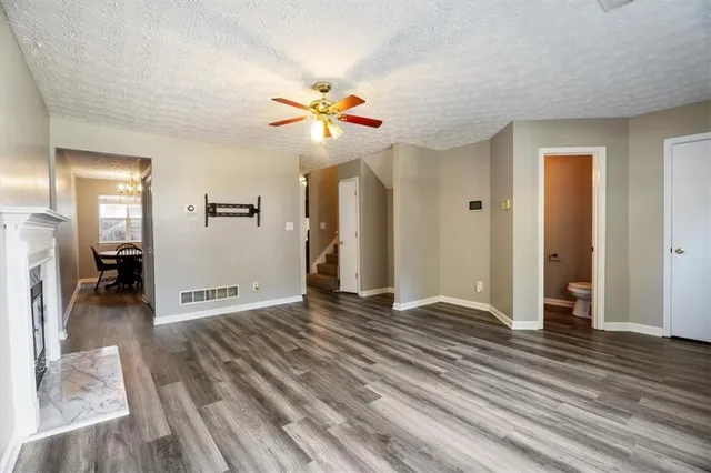 a view of an empty room and kitchen with wooden floor