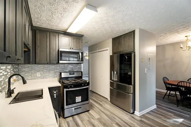 a kitchen with granite countertop a refrigerator and a stove top oven