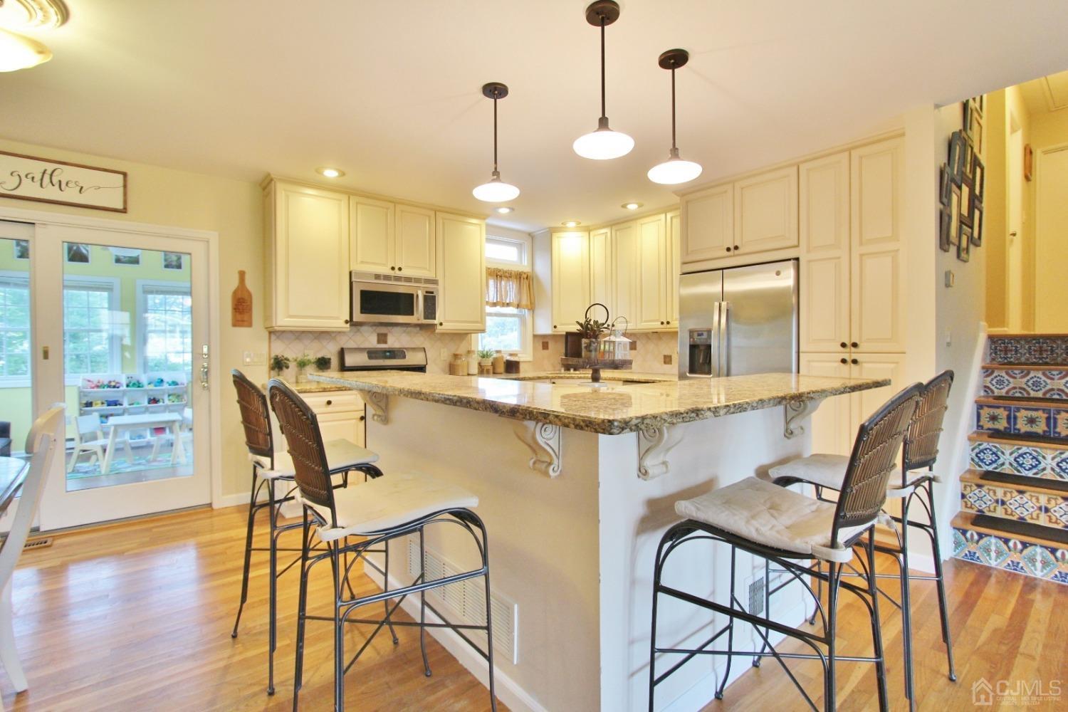 16 Thelma Court Colonia, NJ 07067 - Photo 8 of 37 a kitchen with stainless steel appliances kitchen island granite countertop a stove a refrigerator a sink a dining table and chairs with wooden floor
