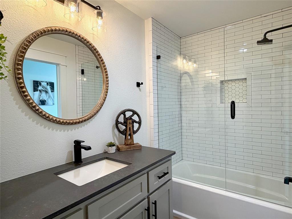 1304 Tinker Road Colleyville, TX 76034 - Photo 21 of 28 a bathroom with a sink a mirror and a shower