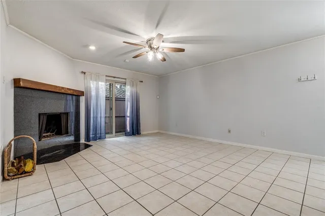 a view of an empty room with a fireplace and a chandelier fan